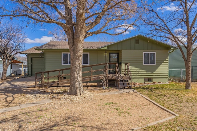 ranch-style home with an attached garage, fence, concrete driveway, a wooden deck, and board and batten siding