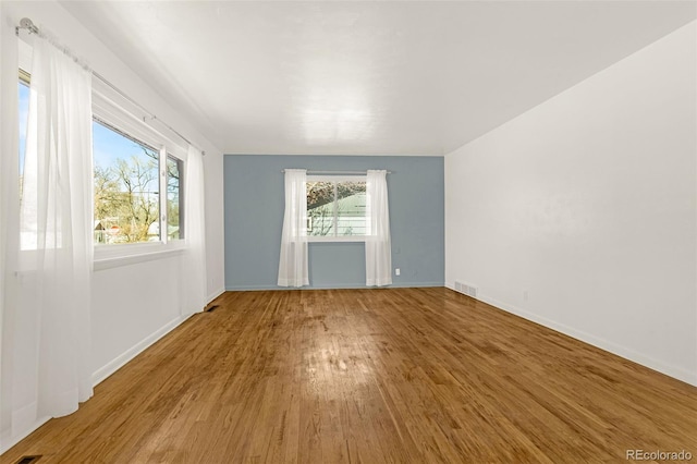 empty room with visible vents, baseboards, and wood finished floors