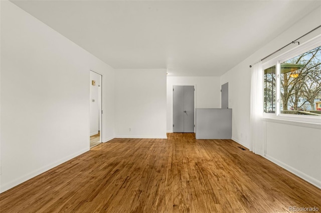 empty room with visible vents, baseboards, and wood finished floors