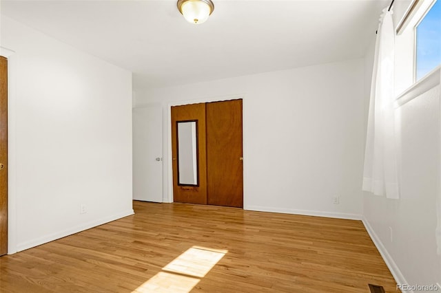 empty room featuring light wood-type flooring, visible vents, and baseboards