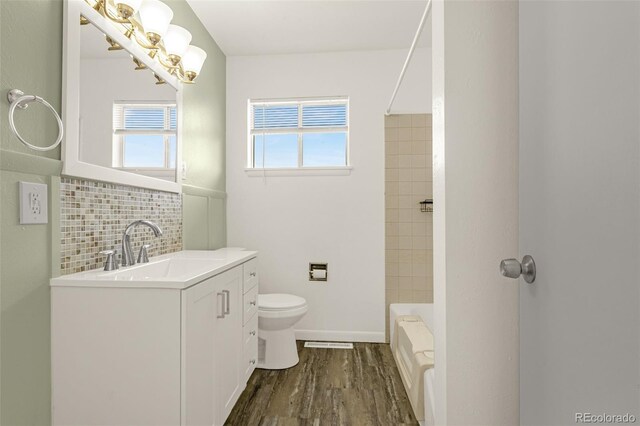 full bath featuring toilet, wood finished floors, vanity, baseboards, and backsplash