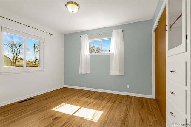 unfurnished bedroom with light wood finished floors, baseboards, and visible vents