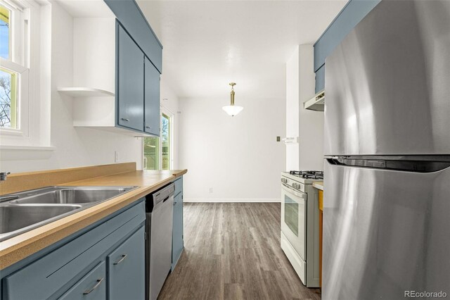 kitchen featuring baseboards, dark wood finished floors, stainless steel appliances, open shelves, and a sink