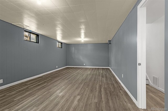 basement featuring wood finished floors, visible vents, and baseboards