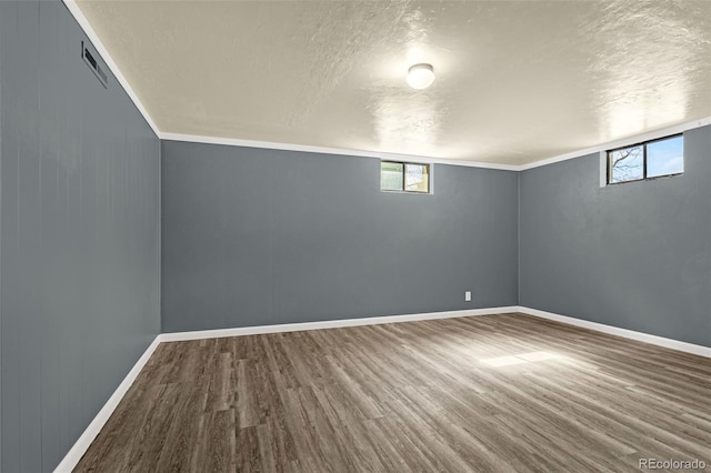 basement with a textured ceiling, baseboards, and wood finished floors