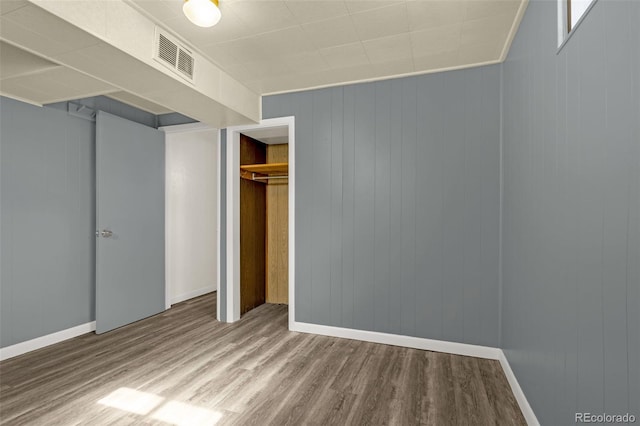 unfurnished bedroom with a closet, visible vents, baseboards, and wood finished floors