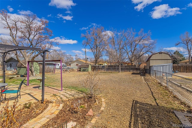 view of yard with a fenced backyard, a patio, an outdoor structure, and a storage unit