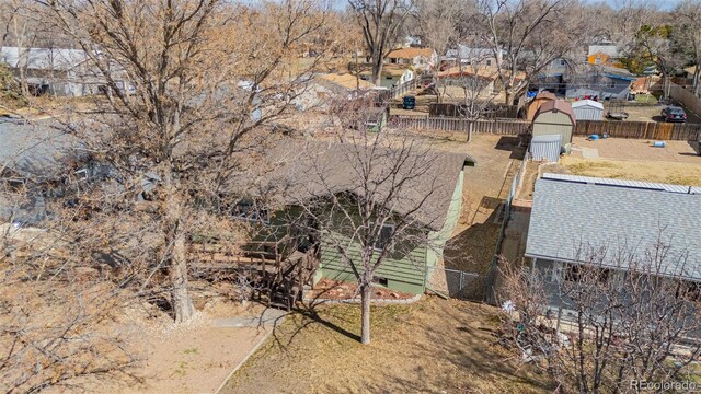 view of property exterior featuring a storage shed, a residential view, fence, and an outbuilding