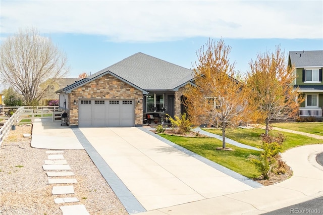 ranch-style home featuring driveway, fence, an attached garage, stone siding, and a front yard