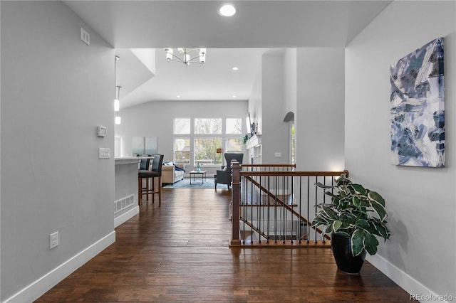 corridor with an inviting chandelier, visible vents, an upstairs landing, and baseboards