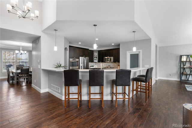kitchen featuring an inviting chandelier, stainless steel appliances, dark wood-style flooring, and light countertops