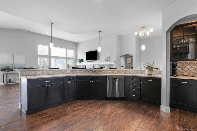 kitchen with stainless steel dishwasher, dark cabinetry, dark wood-style flooring, backsplash, and light countertops