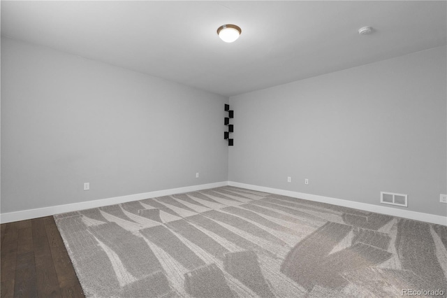 unfurnished room featuring baseboards, visible vents, and wood finished floors