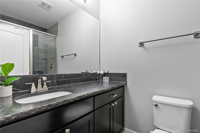full bathroom with toilet, a shower with door, vanity, and visible vents