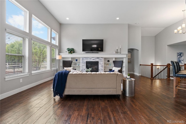 living area featuring baseboards, a notable chandelier, a glass covered fireplace, and hardwood / wood-style flooring