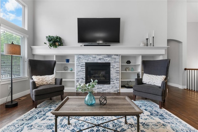 living room with visible vents, wood finished floors, baseboards, and a fireplace