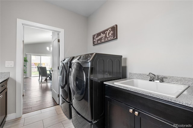 clothes washing area featuring baseboards, washing machine and dryer, cabinet space, and a sink