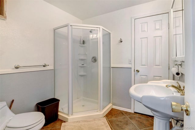 bathroom featuring a stall shower, tile patterned flooring, toilet, and baseboards