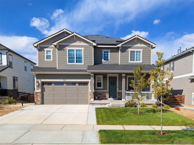 craftsman-style home with a porch, driveway, stone siding, roof mounted solar panels, and a front yard