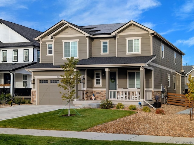 craftsman-style house featuring covered porch, roof mounted solar panels, stone siding, and concrete driveway