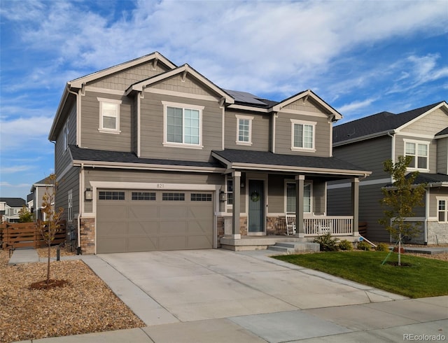 craftsman-style house featuring an attached garage, covered porch, solar panels, concrete driveway, and stone siding