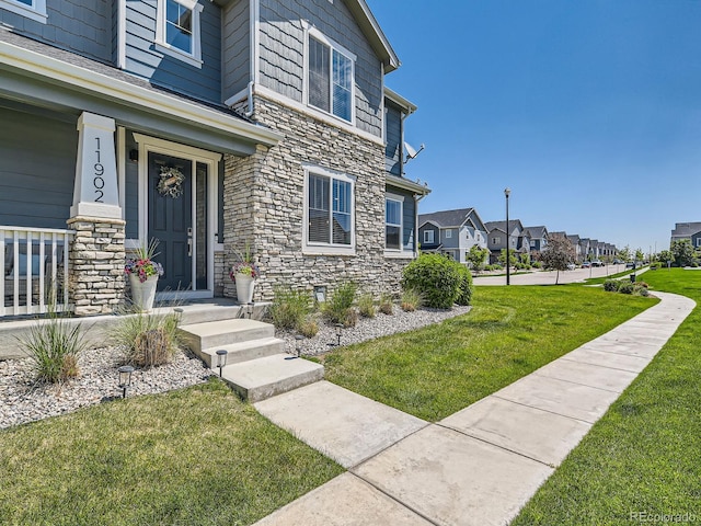 11902 Norfolk Ct, Commerce City, CO 80022 - doorway to property featuring stone siding, a lawn, and a residential view