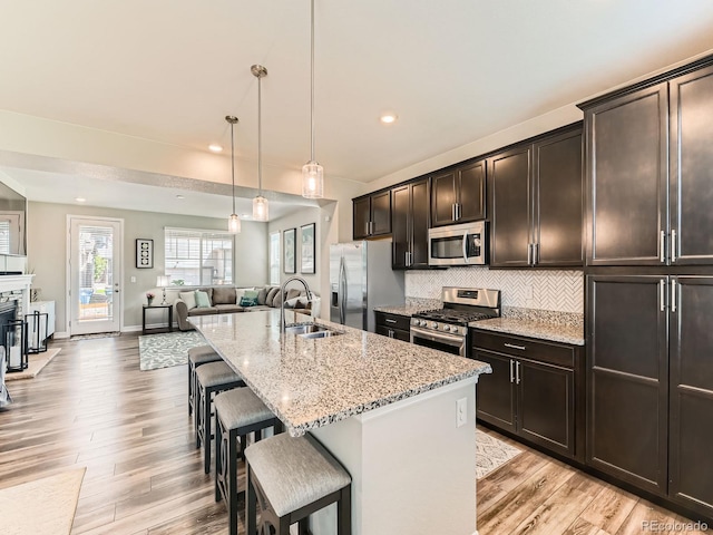 11902 Norfolk Ct, Commerce City, CO 80022 - kitchen with stainless steel appliances, open floor plan, light wood-style flooring, a breakfast bar, and light stone countertops