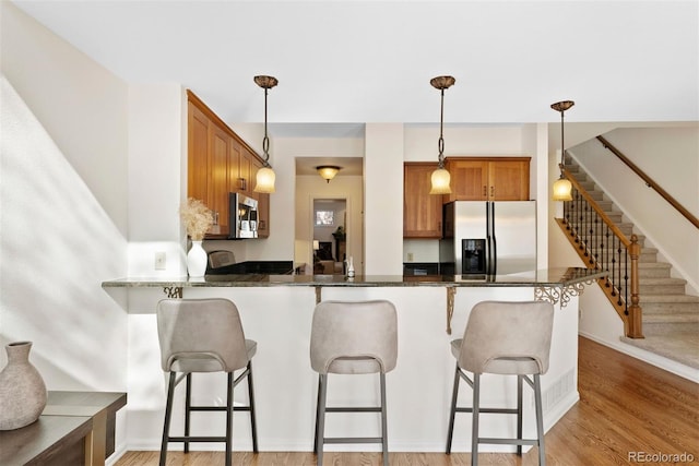 443 Garfield St, Denver, CO 80206 - kitchen featuring appliances with stainless steel finishes, brown cabinetry, a peninsula, and hanging light fixtures