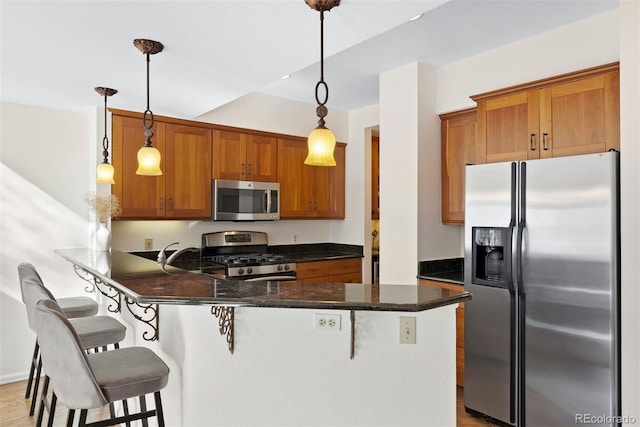 443 Garfield St, Denver, CO 80206 - kitchen featuring appliances with stainless steel finishes, a peninsula, brown cabinets, a breakfast bar area, and decorative light fixtures