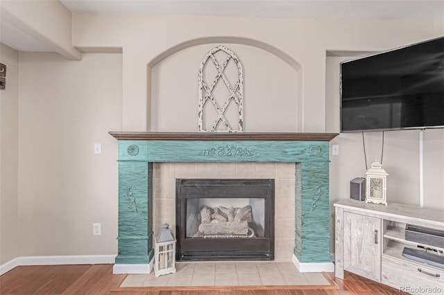 detailed view of wood finished floors, baseboards, and a tile fireplace