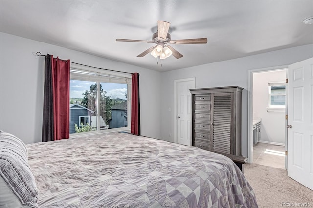 bedroom featuring light carpet, ceiling fan, and ensuite bath
