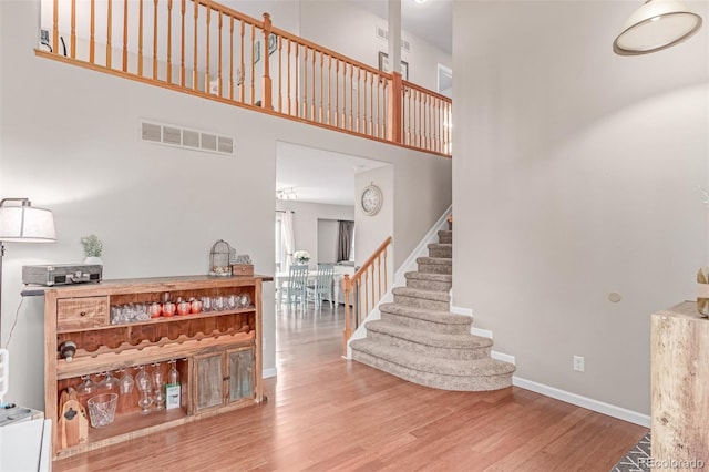stairway with wood finished floors, a high ceiling, and baseboards