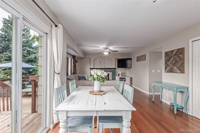 dining area with ceiling fan, wood finished floors, a fireplace, and baseboards