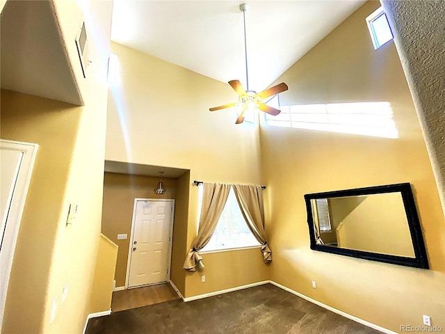 carpeted spare room with a ceiling fan, high vaulted ceiling, visible vents, and baseboards