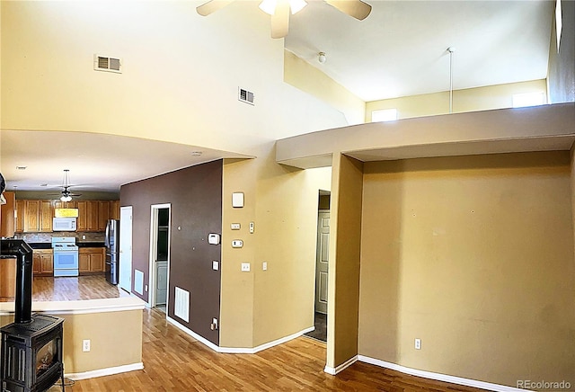 interior space with a ceiling fan, white appliances, wood finished floors, and visible vents