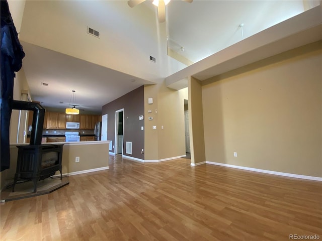 unfurnished living room featuring light wood-style floors, a ceiling fan, baseboards, and visible vents