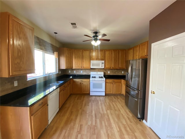 kitchen with backsplash, visible vents, dark countertops, a sink, and white appliances