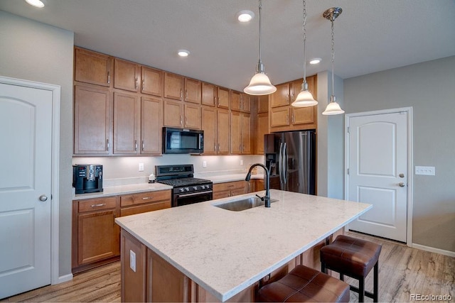 kitchen featuring stainless steel gas stove, black fridge with ice dispenser, a sink, light wood-type flooring, and recessed lighting