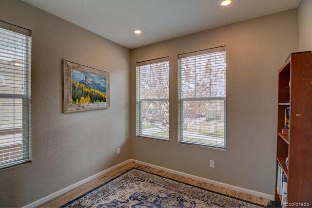 empty room featuring wood finished floors, baseboards, and recessed lighting