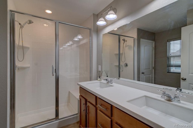 full bathroom with a shower stall, double vanity, and recessed lighting