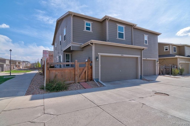 view of front facade with an attached garage, fence, a gate, driveway, and a residential view