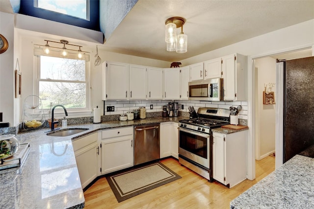 8680 Apache Plume Dr, Parker, CO 80134 - kitchen featuring stainless steel appliances, stone countertops, a sink, decorative backsplash, and light wood finished floors