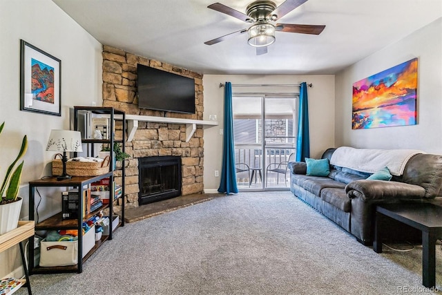 living room featuring ceiling fan, a stone fireplace, and carpet