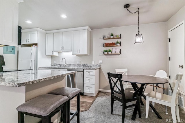 kitchen with white refrigerator, stainless steel dishwasher, light stone countertops, and sink