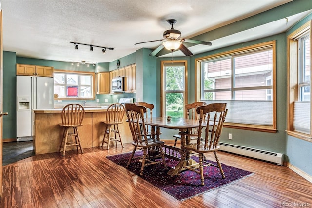 dining area featuring ceiling fan, light hardwood / wood-style flooring, a textured ceiling, and a baseboard heating unit