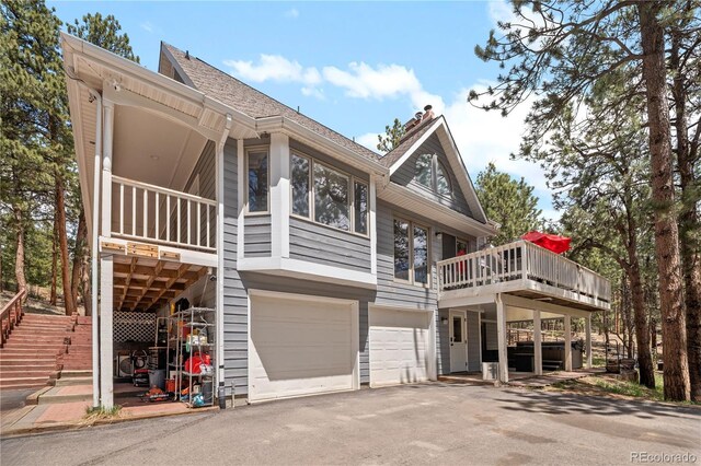 50 Victoria Rd, Pine, CO 80470 - back of property featuring a garage, asphalt driveway, a deck, roof with shingles, and stairway