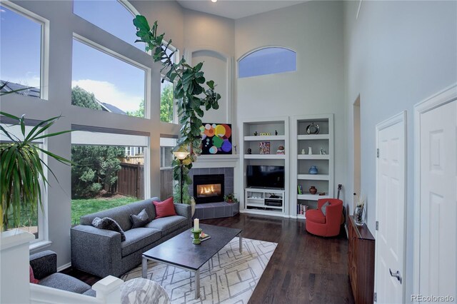 5757 W Alamo Dr, Denver, CO 80123 - living room featuring a towering ceiling, wood-type flooring, a fireplace, built in shelves, and baseboards
