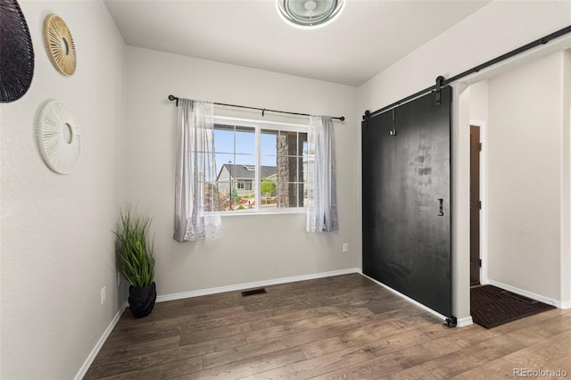 9869 Meridian Hills Trl, Peyton, CO 80831 - unfurnished bedroom featuring a barn door and wood finished floors