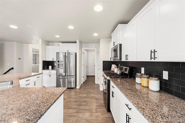 9869 Meridian Hills Trl, Peyton, CO 80831 - kitchen with appliances with stainless steel finishes, wood finished floors, white cabinets, dark stone counters, and recessed lighting