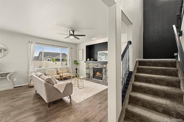 9869 Meridian Hills Trl, Peyton, CO 80831 - living room with wood finished floors, a fireplace, a ceiling fan, stairs, and a textured ceiling